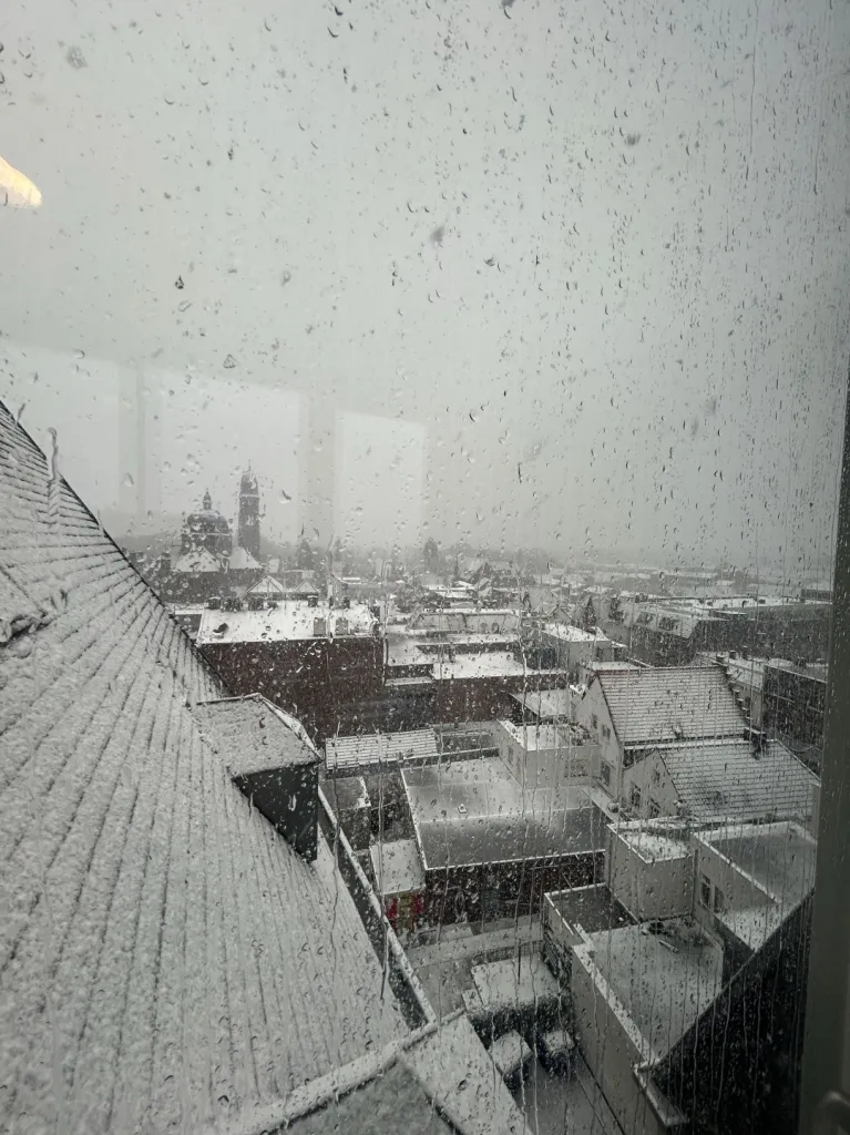 Snowy rooftops and church towers through a wet window