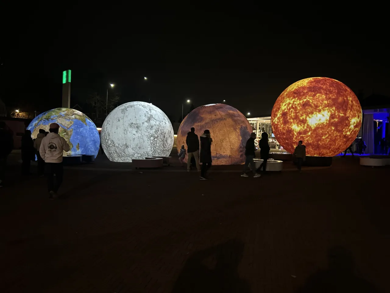 Large illuminated Earth Moon Mars and Sun spheres at a night exhibition